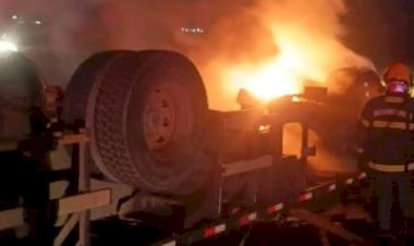 Caminhão carregado de madeira pega fogo após tombar na BR-070