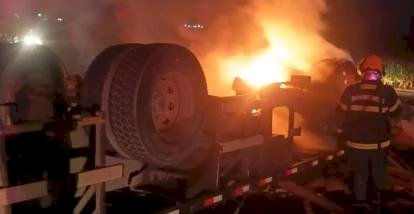 Caminhão carregado de madeira pega fogo após tombar na BR-070